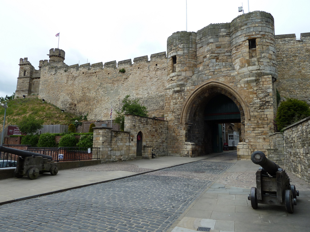 Lincoln Castle gate with cannons in the foreground, the imposing stone arch and battlements behind, on a bright Lincoln day